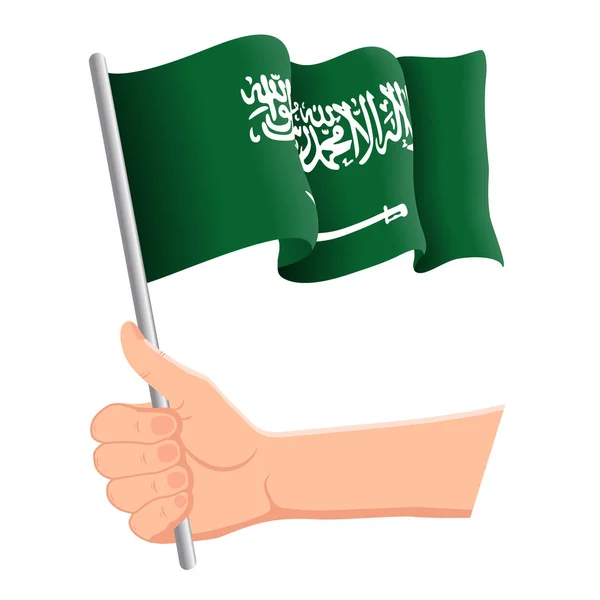 Hand haltend und die Nationalflagge Saudi Arabiens schwenkend. Fans, Unabhängigkeitstag, patriotisches Konzept. Vektorillustration — Stockvektor