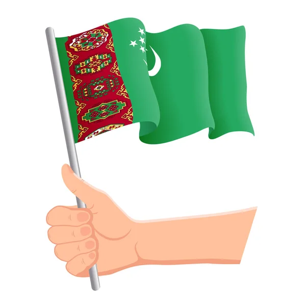 Mão segurando e agitando a bandeira nacional do Turquemenistão. Fãs, dia da independência, conceito patriótico. Ilustração vetorial —  Vetores de Stock