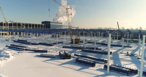 Строительство современного завода или завода, Промышленная зона зимой, панорамный вид с воздуха. Современный завод на заснеженном поле, конструкционная стальная конструкция нового коммерческого здания — стоковое видео