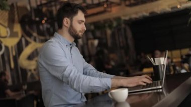Adam bir restoran ya da bar, bir masada bir dizüstü bilgisayar ile adam laptop kafe, Genç hipster adam barda bir kahve molası çalışma, o bir holding ve bağlama ile bir dizüstü bilgisayar, iş adamı