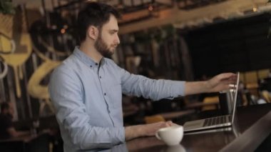 Bir kafe ya da Restoran içinde laptop ile işadamı, çekici erkek işçi kafeteryada bilgisayar kullanıyor
