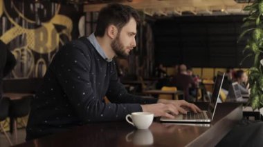 Bir kafe ya da Restoran içinde laptop ile işadamı, çekici erkek işçi kafeteryada bilgisayar kullanıyor