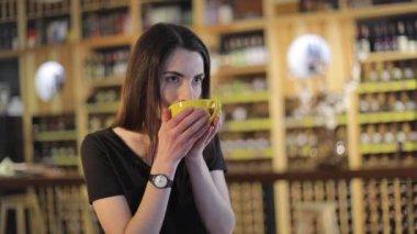 Genç bir kız kahve içer ve bir kafede bir moda dergisi okur veya Restoran, kadın okuma dergi ve içme kahve, şarap raf, arka plan üzerinde Restoran şarap