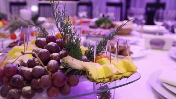 Fruta y comida en la mesa del banquete en el restaurante, trozos de piña y racimos de uvas en la mesa del banquete, decoración de la sala de banquetes, interior del restaurante — Vídeos de Stock