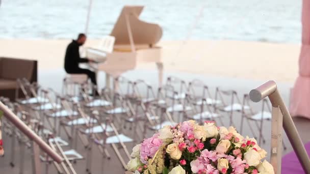 Wedding ceremony on the beach or the river, on a background of a sandy beach, a pianist playing on a white piano — Stock Video