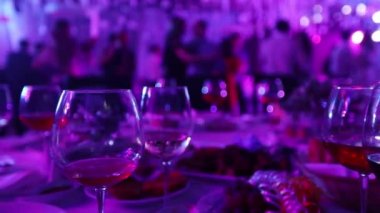 Bir restoran veya bir gece kulübü, alkol ve gıda siluetleri dans insanlar, sahne ışık ve mor dolgu, sığ alan derinliği arka planı ziyafet tablolarla bir gençlik partisi