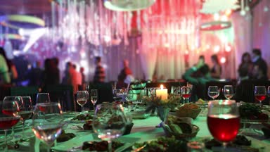 Ziyafet tablosunda bir restoran gözlük ve bir mum. Tablo arka planı dans. Ziyafet tablo, insanlar üzerinde arka plan dans