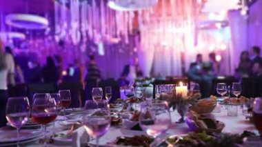 Bir restoran ile gözlük ve bir mum, bir cam ile kırmızı ve beyaz şarap bir yanan bir arka plan üzerine bir ziyafet masada tabloda ziyafet mum, kolye bir tablo içinde bir dekoratif mum mum