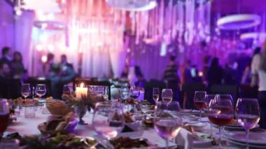 Ziyafet tablosunda bir restoran gözlük ve bir mum. Tablo arka planı dans. Ziyafet tablo, insanlar üzerinde arka plan dans
