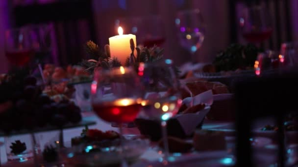 Bankettbord i en restaurang med glasögon och ett ljus, ett glas med rött och vitt vin på ett bankettbord på en bakgrund av en brinnande ljus, en dekorativ vaxljus i Hänget på en tabell — Stockvideo