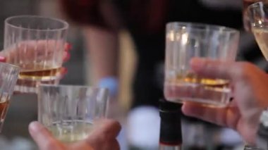 İnsanlar alkol bardak ve kadeh viski ile masada kutlamak. Bardak viski yakın çekim insanlarla elleri. Sığ derinlik-in tarla