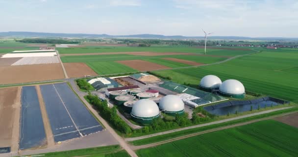 Usine pour la production de biogaz dans le champ vert, usine pour la production de biogaz dans le contexte des éoliennes vue d'en haut — Video