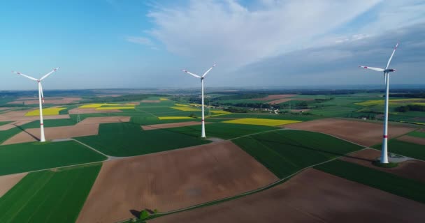 Vol au-dessus des champs agricoles verts aux éoliennes se tenant au loin — Video