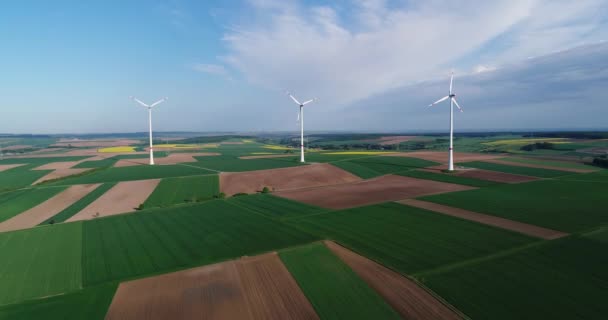 Panoramy powietrzne pól uprawnych i generatorów wiatrowych produkujących energię elektryczną. Nowoczesne technologie pozyskiwania alternatywnej energii wiatrowej. Widok z lotu ptaka — Wideo stockowe