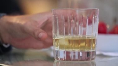 Adam bir bardak viski buz tablosundan alır, bir bardak buzlu viski koyar tablo, yakın çekim, sığ derinlik-in tarla, ahşap masa üzerinde businessmans elinde viski bardak.