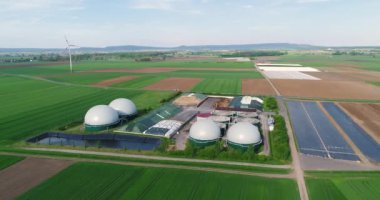 Yeşil alanda biyogaz üretimi için bitki, yukarıdan rüzgar jeneratörleri görünümün arka planına karşı biyogaz üretimi için bitki