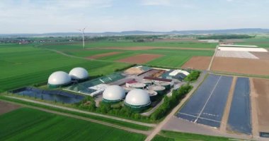 Yeşil alanda biyogaz üretimi için bitki, yukarıdan rüzgar jeneratörleri görünümün arka planına karşı biyogaz üretimi için bitki