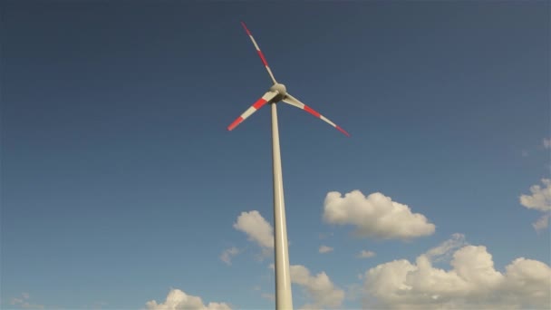 Generatore di vento sullo sfondo di nuvole che galleggiano nel cielo. Rotazione delle grandi pale del generatore eolico. Vista panoramica sul paesaggio agricolo. Giornata di sole. L'Europa. Timelapse — Video Stock