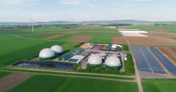 Usine pour la production de biogaz dans le champ vert, usine pour la production de biogaz dans le contexte des éoliennes vue d'en haut — Video