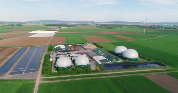 Anlage zur Erzeugung von Biogas auf der grünen Wiese, Anlage zur Erzeugung von Biogas vor dem Hintergrund von Windkraftanlagen Blick von oben — Stockvideo