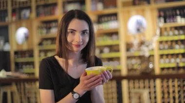 Aroma ve lezzet kahve kahve dükkanında dinlenirken zevk kız ile bir fincan kahve, bir restoranda. Genç güzel mutlu gülümseyen kız kupa sıcak kahve veya çay ile tutarak