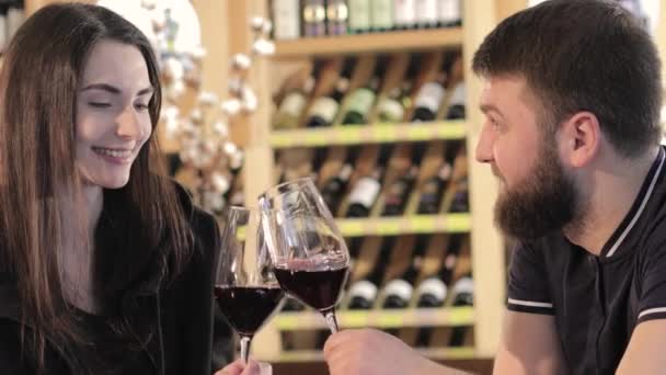 Een meisje en een jongen in een restaurant communiceren en drink rode wijn, een jong koppel drinkt rode wijn op een tafel in een restaurant of café — Stockvideo