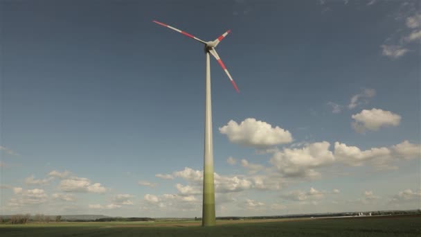 Generador de viento contra el fondo de nubes flotando en el cielo. Rotación de las grandes palas generadoras de viento. Vista panorámica del paisaje agrícola. Día soleado. Europa. Cronograma — Vídeo de stock