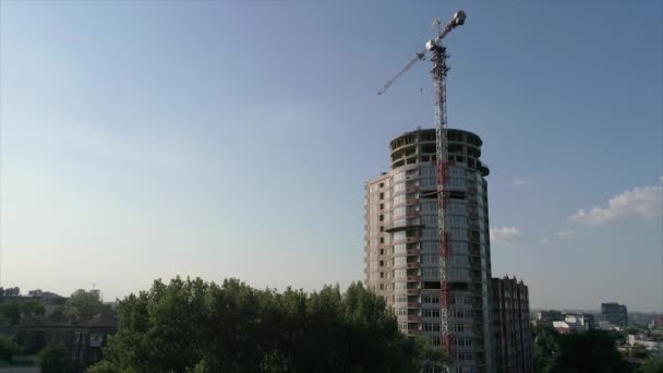 Construção de uma casa alta de vários andares, um guindaste de torre em um canteiro de obras, uma vista da construção de um edifício moderno de arranha-céus, uma paisagem urbana — Vídeo de Stock