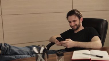 Ofiste işadamı cep telefonundan bir oyun oynuyor. Kişi yüzüne parlak duygular. Genç adam akıllı telefon kullanarak office ile çalışma