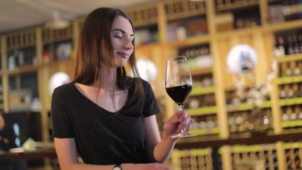 Γυναίκα που έχει ένα ποτήρι κόκκινο κρασί, ένα κορίτσι με ένα ποτήρι κόκκινο κρασί, μια νεαρή όμορφη κοπέλα πόσιμο κόκκινο κρασί σε ένα εστιατόριο — Αρχείο Βίντεο