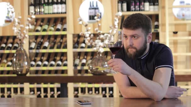 Egy magányos férfi, egy pohár vörös bor, egy étterem, egy pohár vörös bor, a fiatalember egy férfi italok vörös bor egy asztalnál egy étteremben — Stock videók