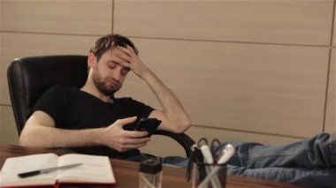 Ofiste işadamı cep telefonundan bir sosyal ağ iletişim kurar. Kişi yüzüne parlak duygular. Genç adam akıllı telefon kullanarak office ile çalışma