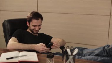 Ofiste işadamı cep telefonundan bir sosyal ağ iletişim kurar. Kişi yüzüne parlak duygular. Genç adam akıllı telefon kullanarak office ile çalışma