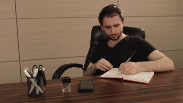 Homme d'affaires prenant des notes avec fond d'ordinateur portable. Un homme d'affaires écrit dans un cahier à une table. Concept d'entreprise — Video