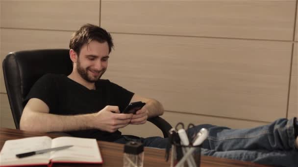 Geschäftsmann spielt auf seinem Handy ein Spiel. helle Emotionen auf dem Gesicht der Personen. Junger Mann arbeitet vom Büro aus mit Smartphone — Stockvideo