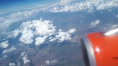 Uçak penceresinden görüntülemek için mavi gökyüzü ve beyaz bulutlar, bir turuncu türbin kanat uçağın gökyüzünde bulutlar, beyaz bulutlar float yerden dünyadan bir görünümünü