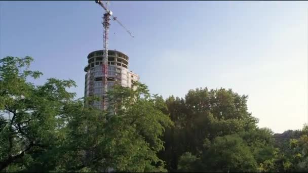 Construção de uma casa alta de vários andares, um guindaste de torre em um canteiro de obras, uma vista da construção de um edifício moderno de arranha-céus, uma paisagem urbana — Vídeo de Stock