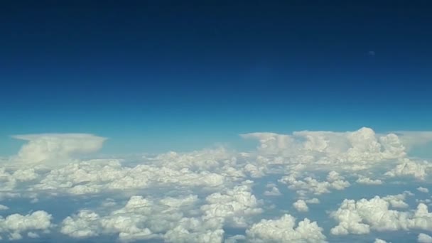 Pohled z okna letadla na modrou oblohu a bílé mraky za slunečného dne, spousta float bílé mraky nad zemí, pohled na zemi přes bílý načechraný mraky — Stock video