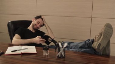 Ofiste işadamı cep telefonundan bir oyun oynuyor. Kişi yüzüne parlak duygular. Genç adam akıllı telefon kullanarak office ile çalışma