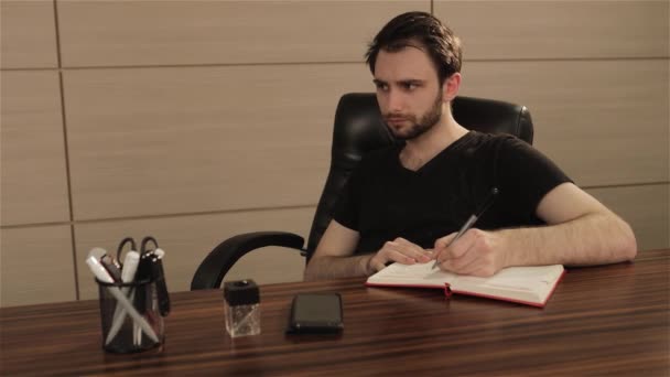 Homme d'affaires prenant des notes avec fond d'ordinateur portable. Un homme d'affaires écrit dans un cahier à une table. Concept d'entreprise — Video