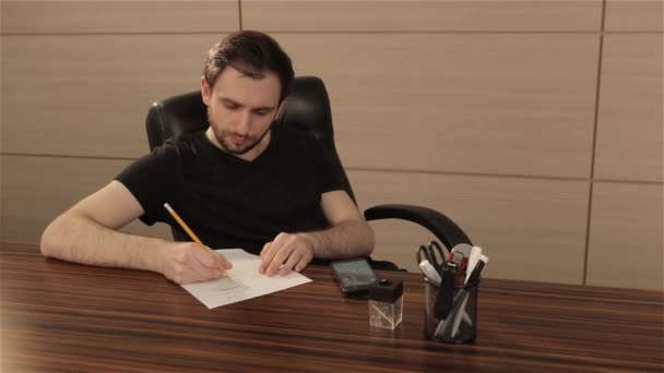 The office worker counts on the calculator and writes the results on a white sheet — Stock Video