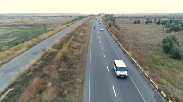 Шоссе за пределами города панорамный вид сверху, шоссе вдоль поля, автомобили идут, мотоцикл движется по дороге, движение — стоковое видео