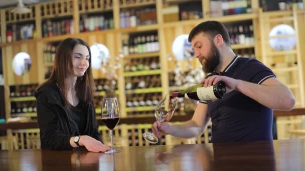 Uma menina e um cara em um restaurante se comunicam e bebem vinho tinto, um jovem casal bebe vinho tinto em uma mesa em um restaurante ou café. — Vídeo de Stock