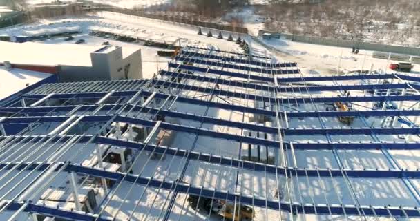 Construcción de una fábrica o planta moderna, zona industrial en invierno, vista panorámica desde el aire. Moderna planta en el campo cubierto de nieve, la estructura de acero estructural de un nuevo edificio comercial — Vídeo de stock