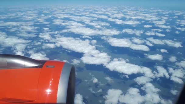 Όμορφη θέα από το παράθυρο του αεροπλάνου προς τον μπλε ουρανό και άσπρα σύννεφα, σύννεφα λευκό επιπλέουν πάνω από το έδαφος — Αρχείο Βίντεο