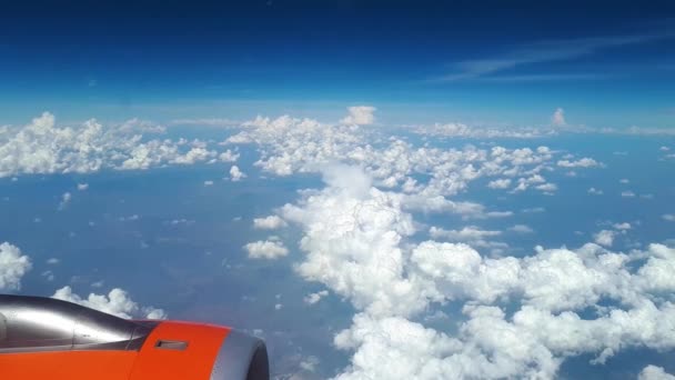 มุมมองที่สวยงามจากหน้าต่างเครื่องบินไปยังท้องฟ้าสีฟ้าและเมฆสีขาว เมฆสีขาวลอยอยู่เหนือพื้นดิน — วีดีโอสต็อก