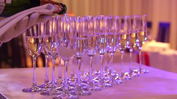 El camarero vierte champán en vino, en un restaurante, El camarero vierte champán en copas de cristal, Interior del restaurante, mesa buffet, Camarero en guantes blancos, primer plano — Vídeo de stock