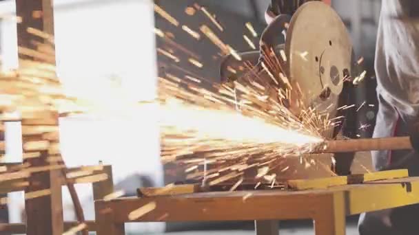 Metal cutting saw cuts a thin square tube, orange sparks from metal cutting saw — Stock Video