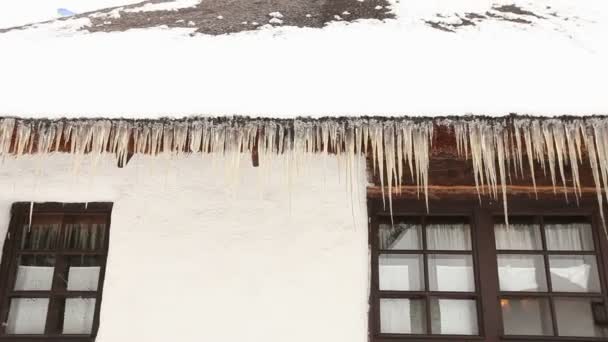木小屋与冰柱在屋顶上, 冰柱挂在屋顶上的木房子, 农村木房子与茅草屋顶, 粘土小屋与雪屋顶上, 老房子, 冰柱挂起 — 图库视频影像