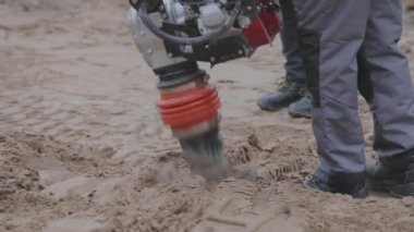 İnşaat alanında çalışan işçiler, rammer 'ı dolduran işçiler. Tamping toprağı